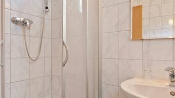 A bathroom with a glass-enclosed shower, a sink, and a mirror.