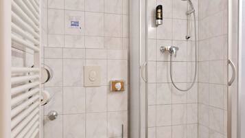 Un baño moderno con inodoro, ducha con cabezal de ducha manual y toallero.