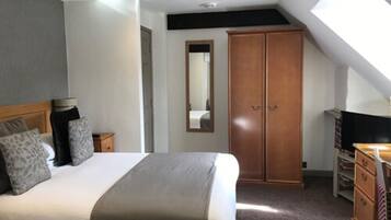 A bedroom with a bed, a wardrobe, a mirror, and a television.