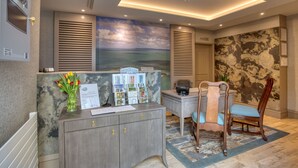 A reception desk with a view of the sea, a marble wall, and a ceiling with recessed lighting. - La Barbarie Hotel by Eight Continents (St. Martins)