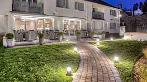 A two-story building with a well-lit entrance, outdoor seating area, and a paved pathway. - La Barbarie Hotel by Eight Continents (St. Martins)