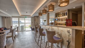 A modern bar area with a marble countertop, bar stools, and overhead lighting. - La Barbarie Hotel by Eight Continents (St. Martins)
