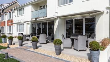 A modern house with a patio area featuring outdoor furniture and potted plants.