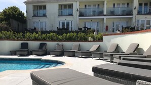 Un área junto a la piscina con sillones de descanso y una pileta.