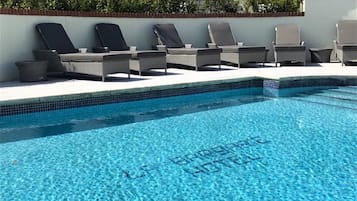 Una piscina al aire libre, sombrillas, tumbonas