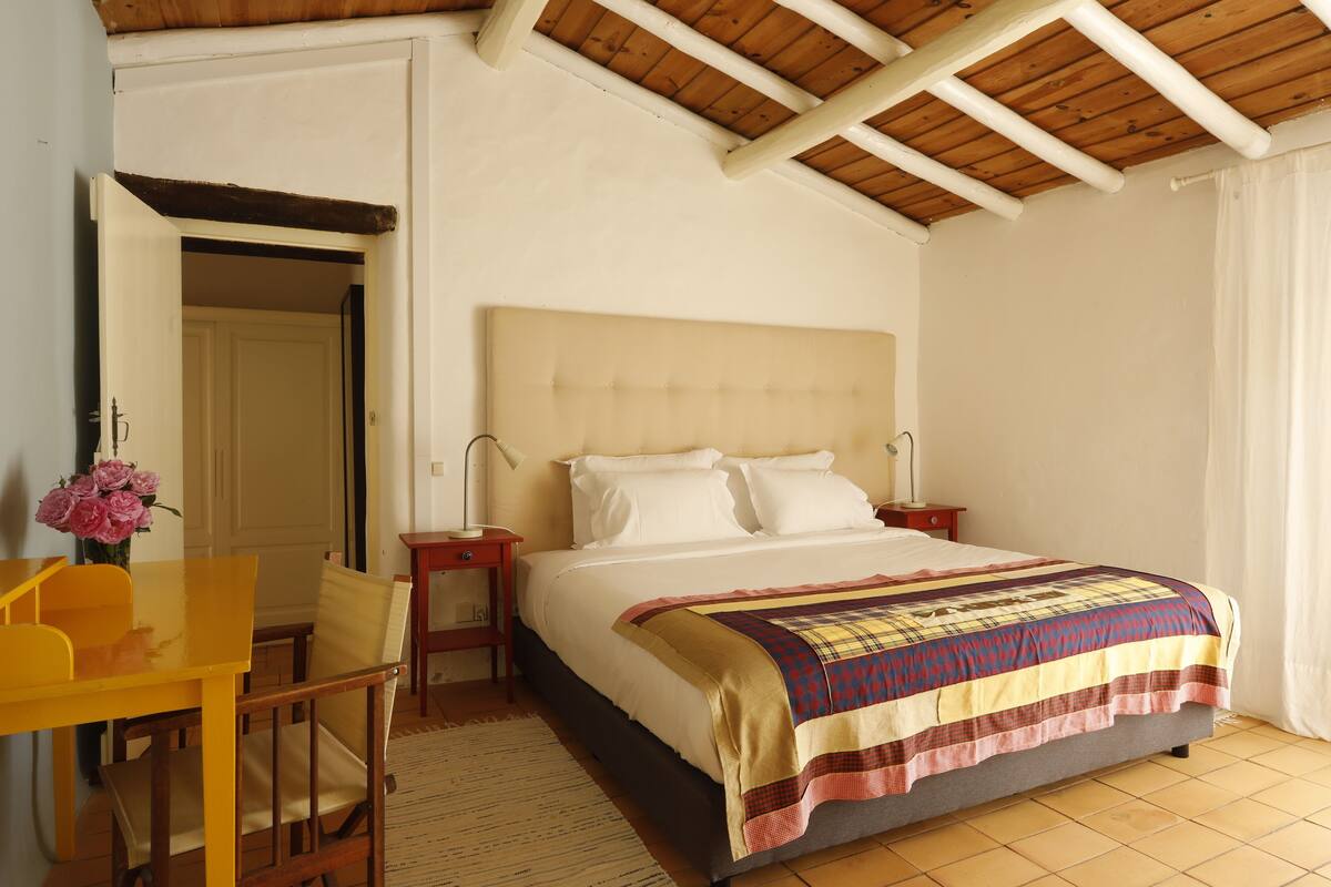 A bedroom with a bed, a desk, and a chair.
