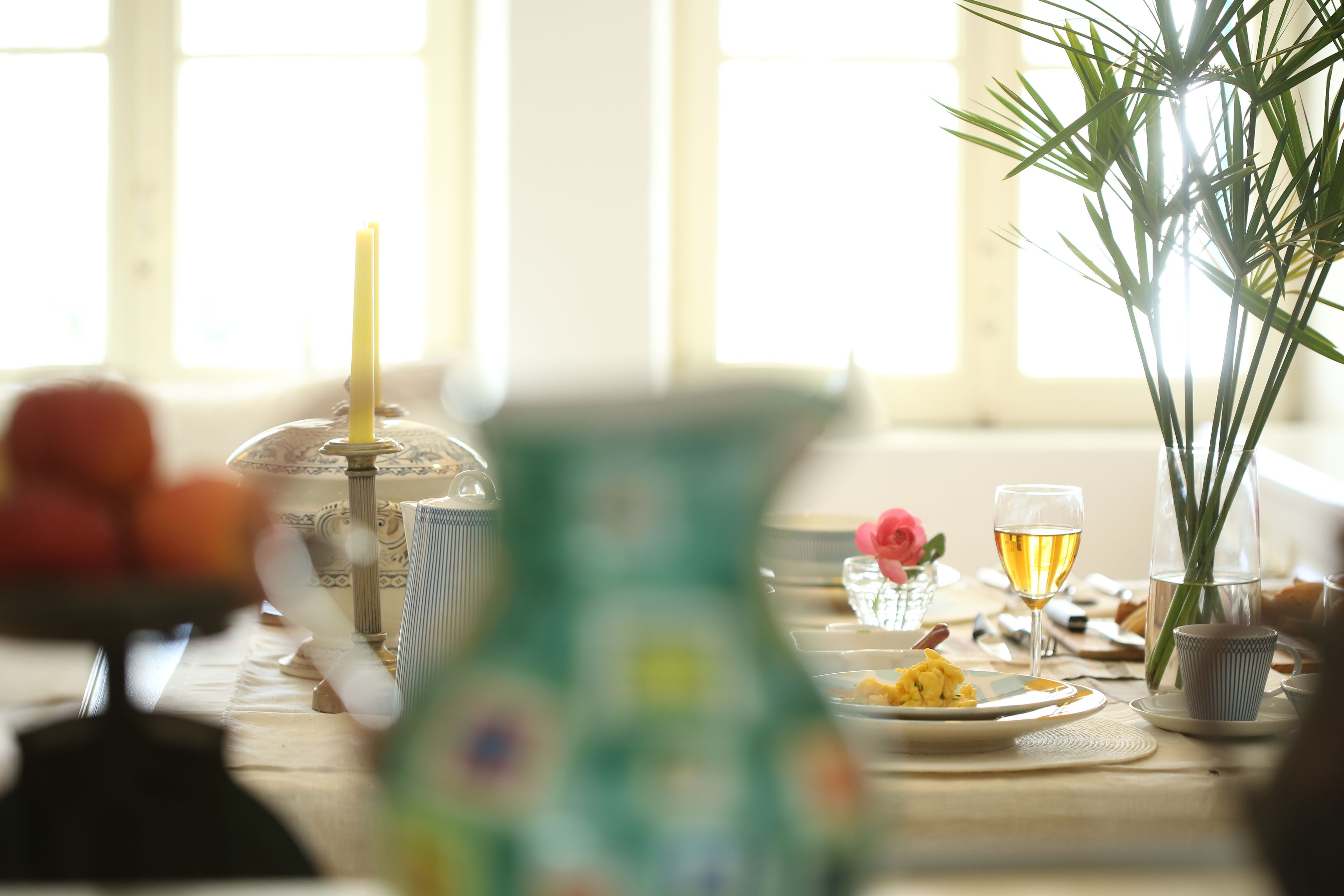 Una mesa de comedor con diversos platos, una copa de vino y un florero con flores.