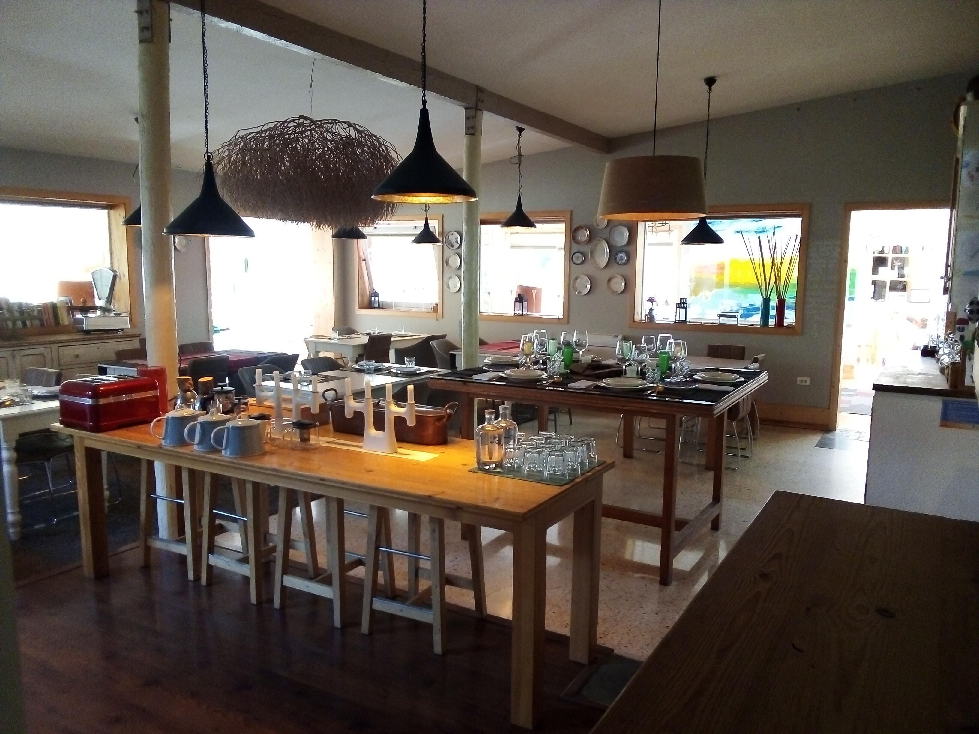 Una cocina amplia con encimeras de madera, luces colgantes y una zona de comedor con una larga mesa dispuesta para una comida.