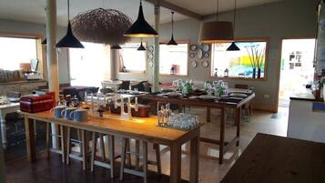 Una cocina amplia con encimeras de madera, luces colgantes y una zona de comedor con una larga mesa dispuesta para una comida.