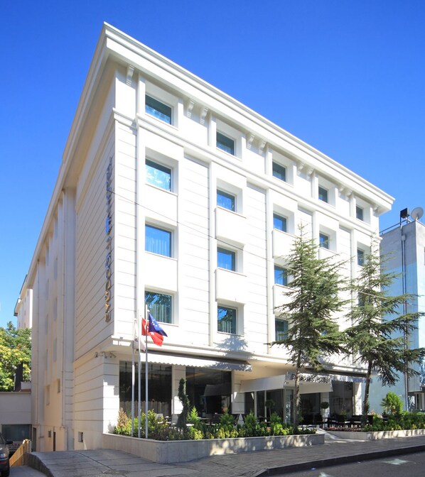 A white building with multiple windows and a flag. - Eyuboglu Hotel (Ankara)
