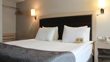A hotel room with a large bed, two bedside lamps, a bedside table, and a wardrobe.