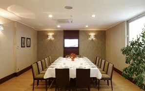 A conference room with a long table set for a meeting, surrounded by chairs, with a television screen and wall sconces on the walls. - Eyuboglu Hotel (Ankara)
