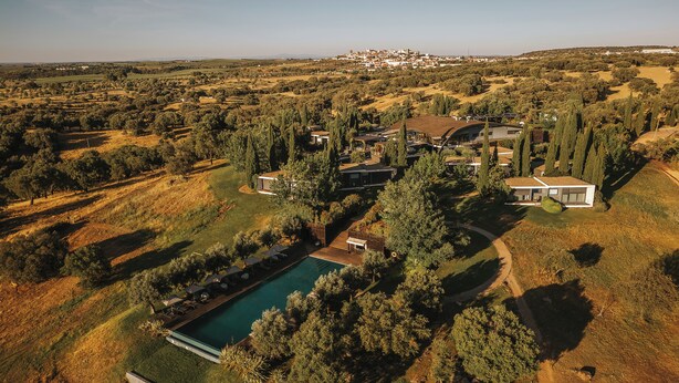 Vista aérea de una zona residencial con piscina, casas modernas y zonas verdes circundantes.