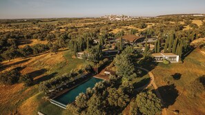 An aerial view of a residential area with a swimming pool, modern houses, and surrounding greenery. - Herdade Da Cortesia Hotel (Avis)