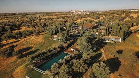 An aerial view of a residential area with a swimming pool, modern houses, and surrounding greenery.. Herdade Da Cortesia Hotel