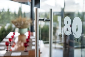 Se ve a través de un ventanal un letrero de restaurante que muestra el número 180 y la palabra 'RESTAURANTE'.