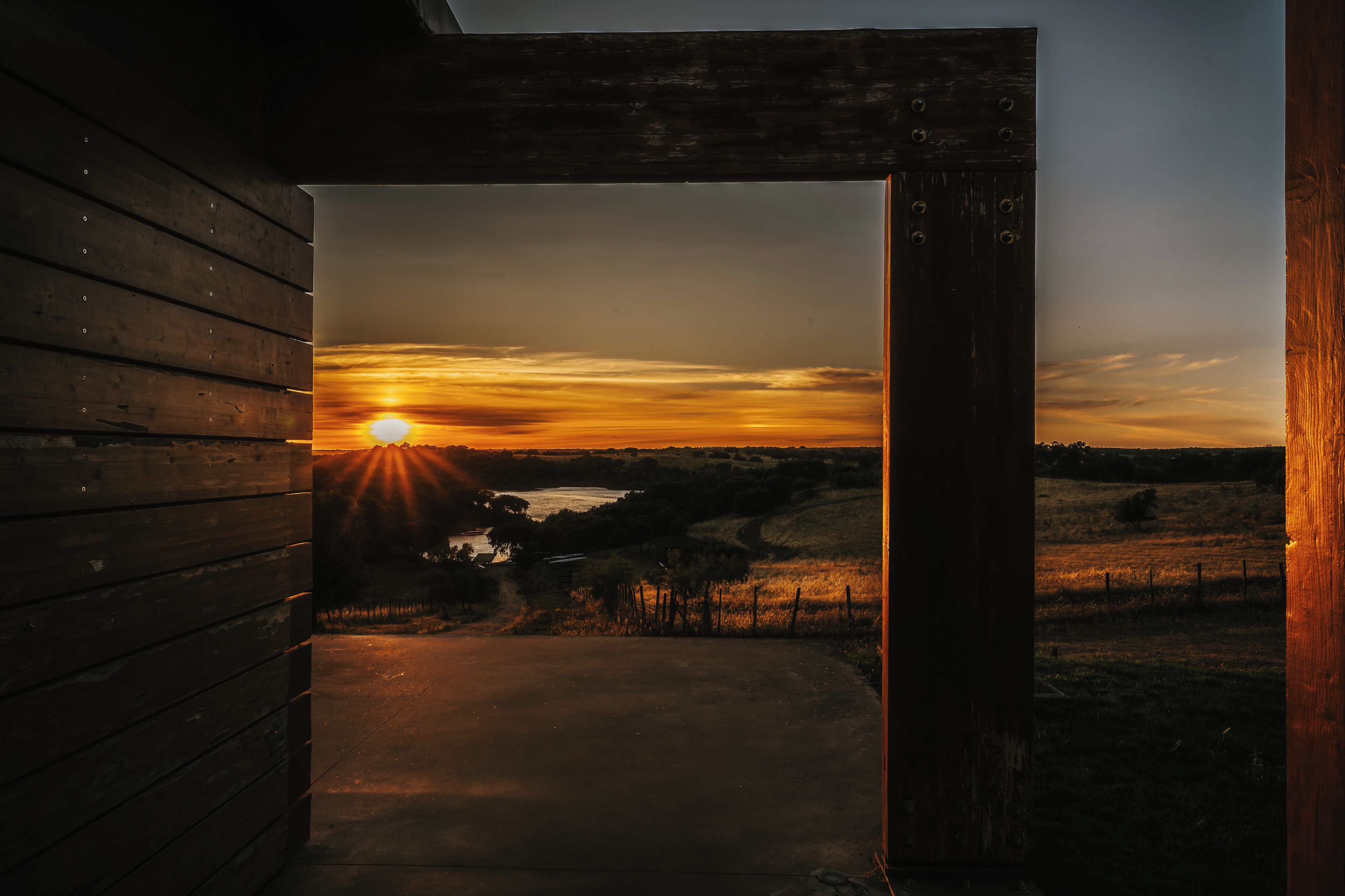 A wooden structure with a view of a sunset over a landscape.