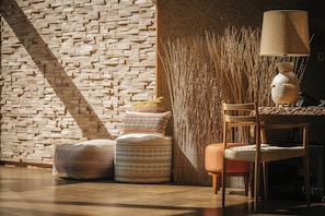 Una habitación con pared de ladrillo, un separador tejido y una lámpara sobre una mesa.
