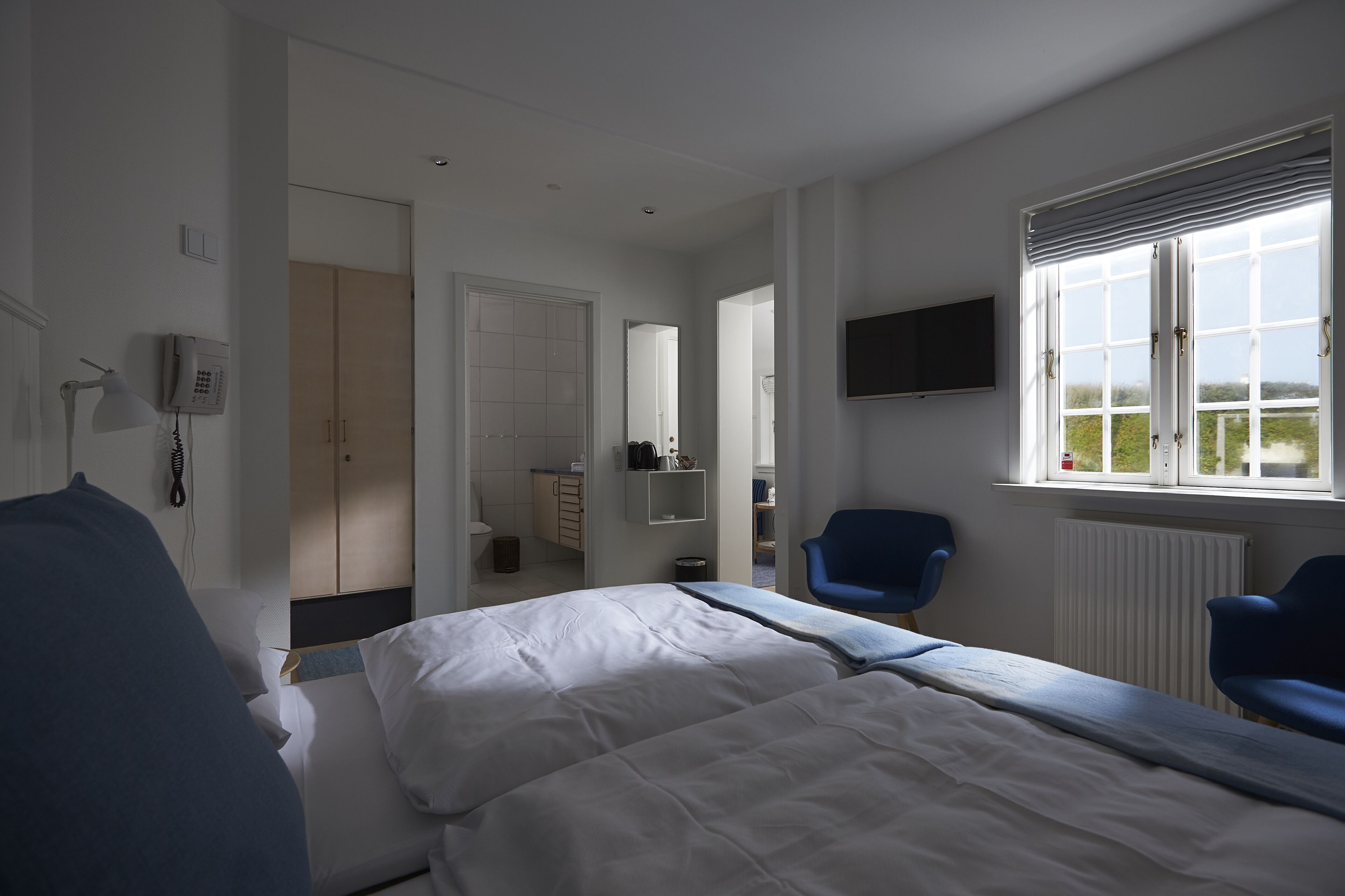 Et hotelværelse med seng, skrivebord, stol, fjernsyn og et vindue med udsigt.