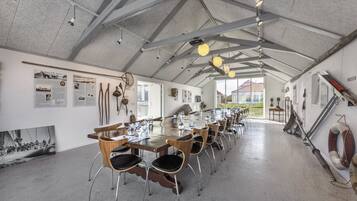 Una larga mesa de comedor con sillas, un techo alto con vigas a la vista y decoración temática náutica.