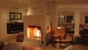 A cozy living room with a fireplace, comfortable seating, and a bookshelf. - Ruths Hotel (Skagen)