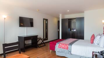 Quarto de hotel moderno com cama, escrivaninha, cadeira e televisão.