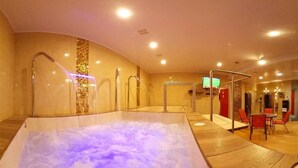 Un área de jacuzzi con suelo de madera, pared de azulejos y una pantalla de televisión montada en la pared.