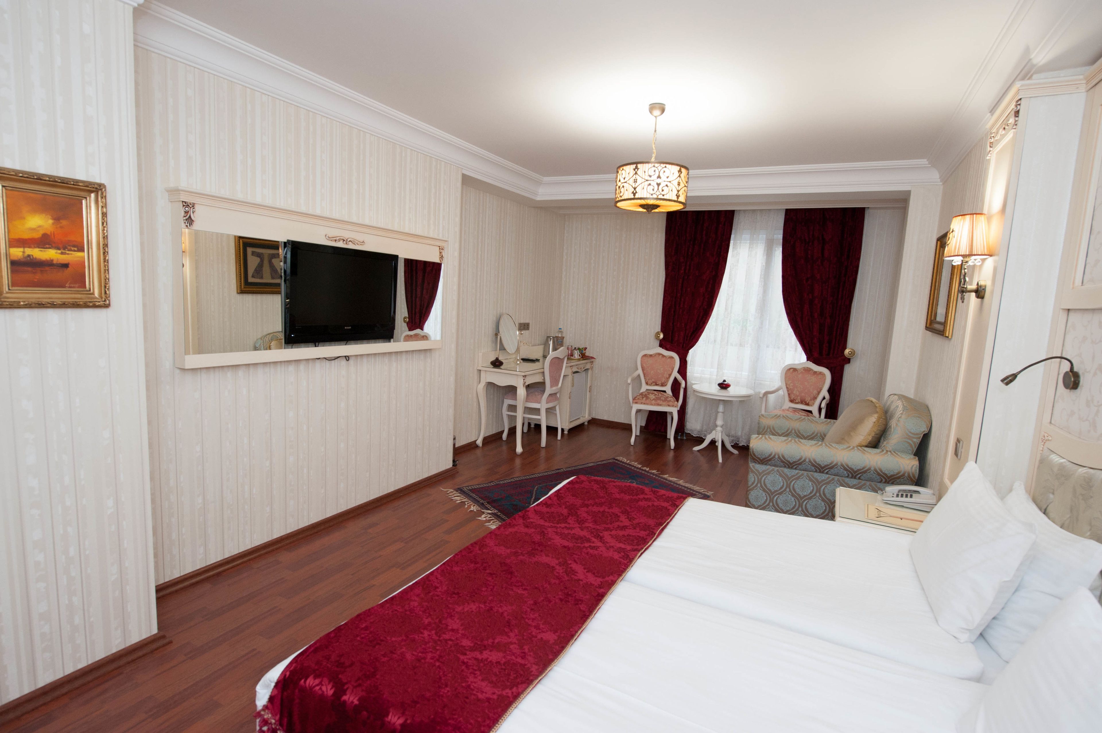 A hotel room with a bed, a TV, a desk, a chair, and a sofa.