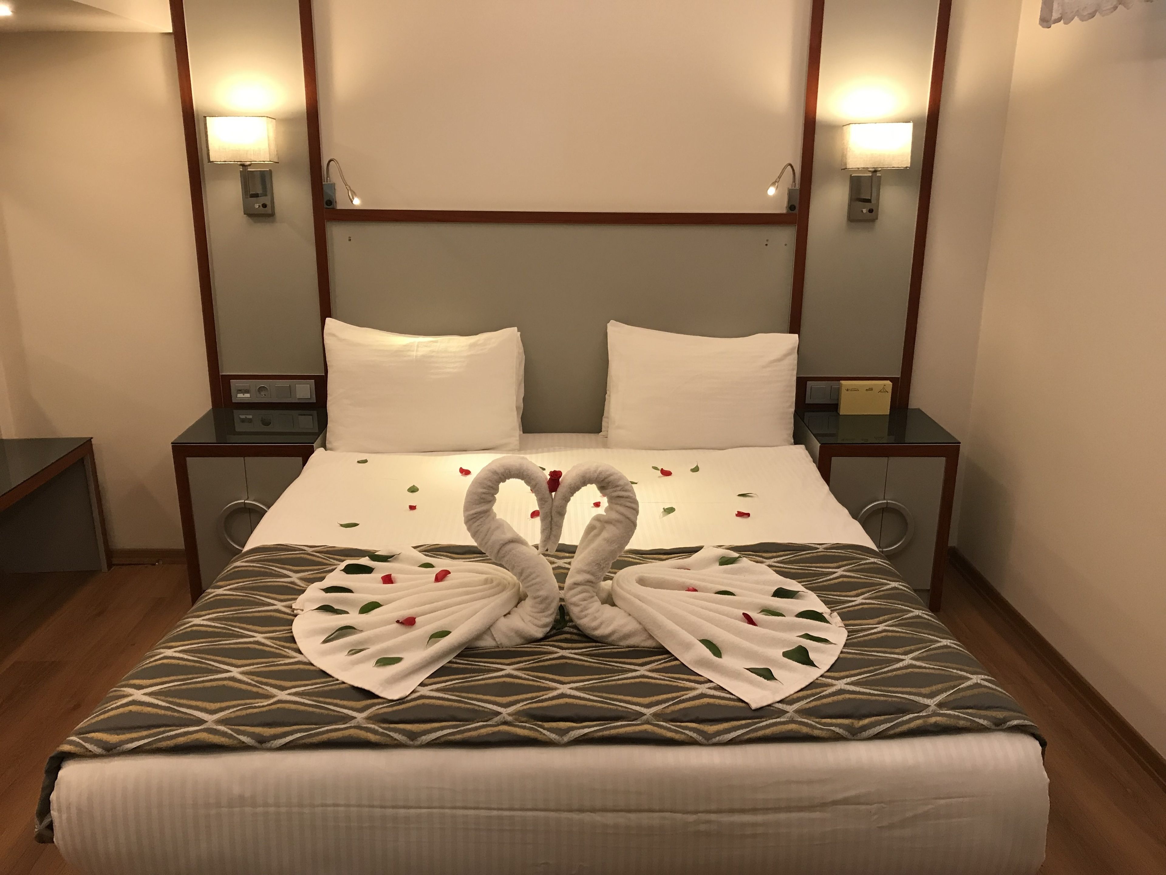 A hotel room with a bed, two nightstands, and a mirror above the bed.