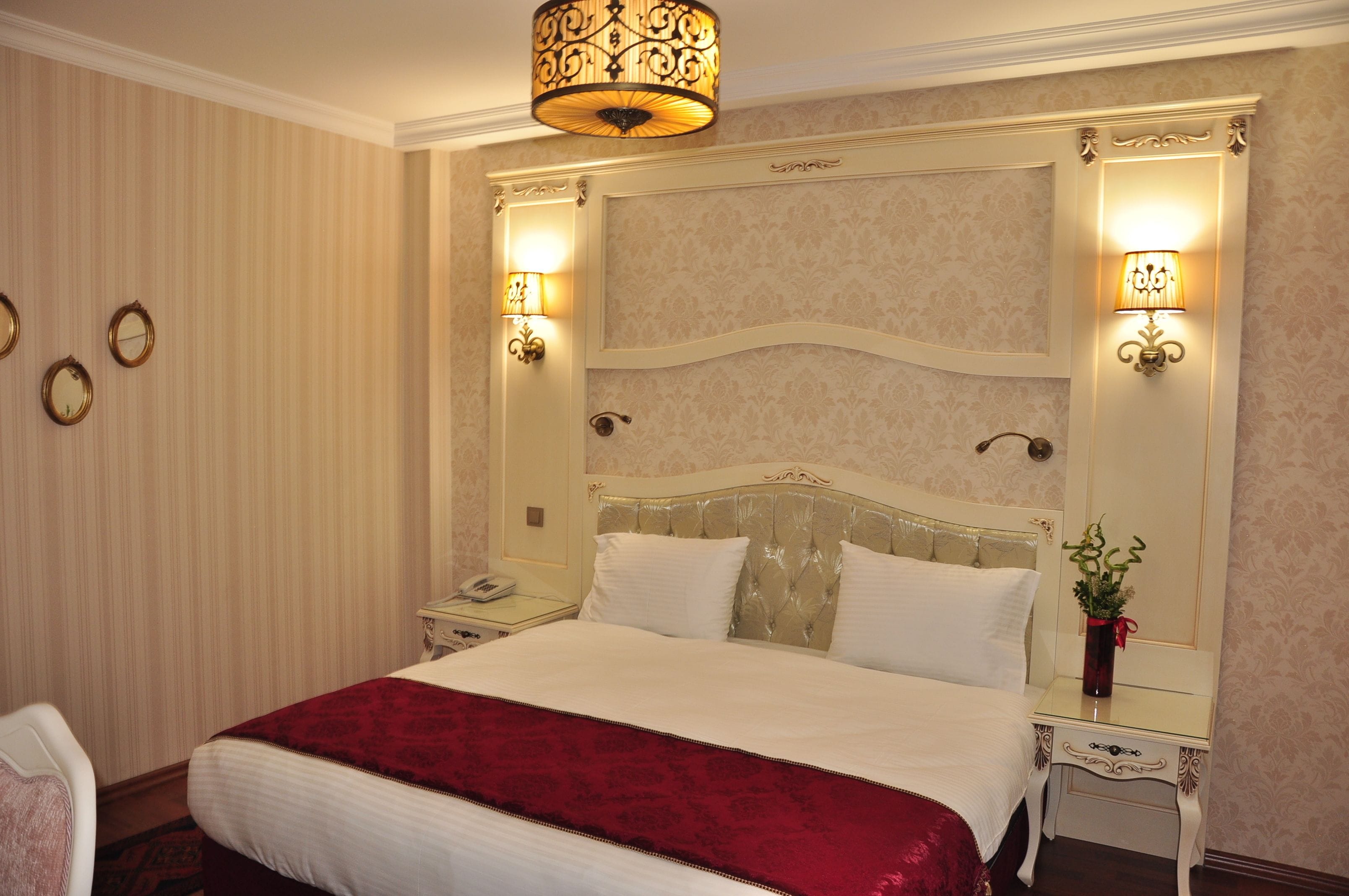 Une chambre d’hôtel avec un grand lit, deux tables de chevet, une petite table, une lampe et un miroir au mur.