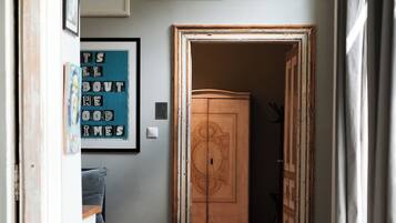 Un corridoio con pavimento in legno, un tappeto decorato e un armadio con pannello decorativo.