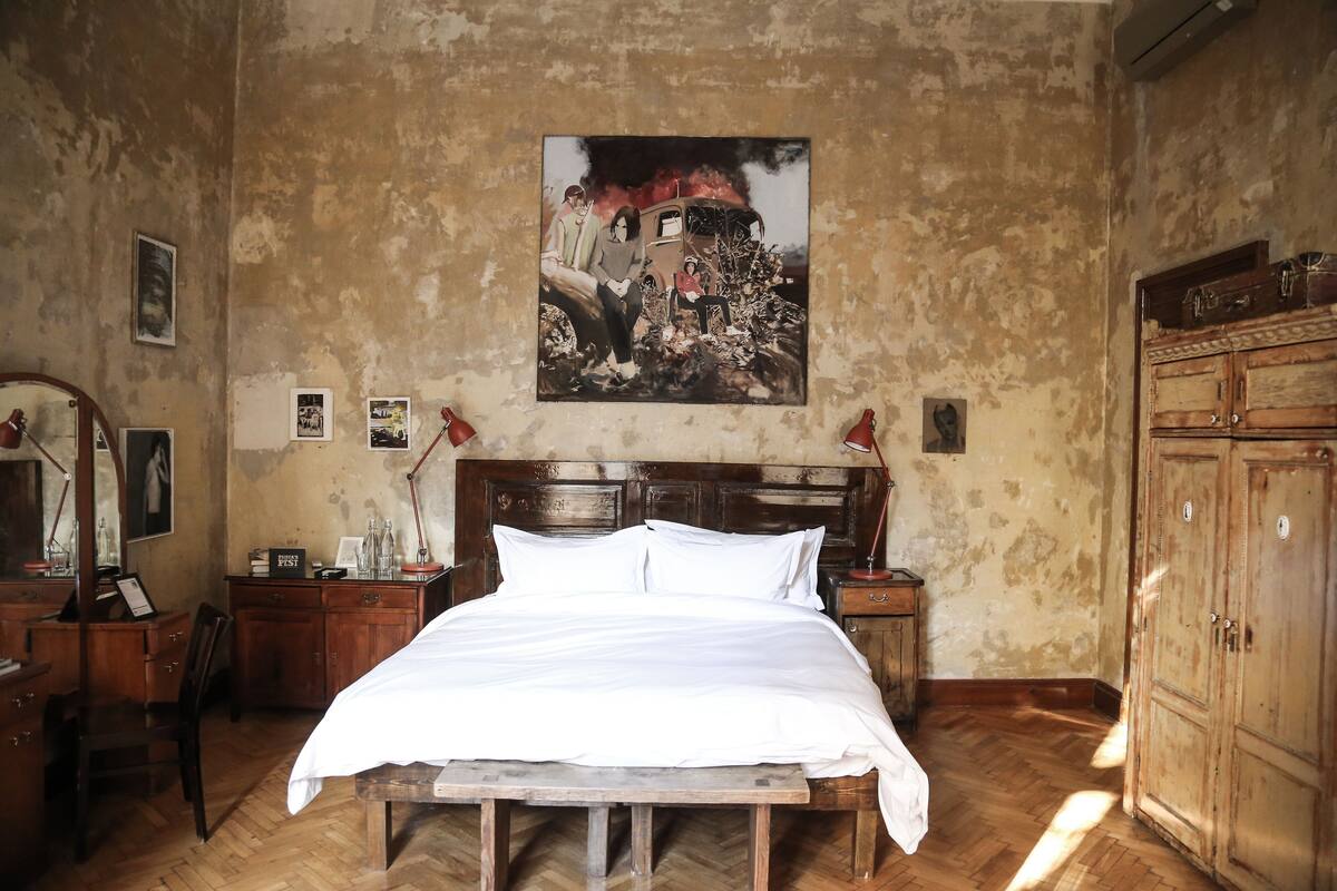 A bedroom with a wooden bed, a wooden wardrobe, a wooden desk, and a wall-mounted picture.