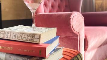 A pink upholstered sofa with a stack of books and a martini glass on it.