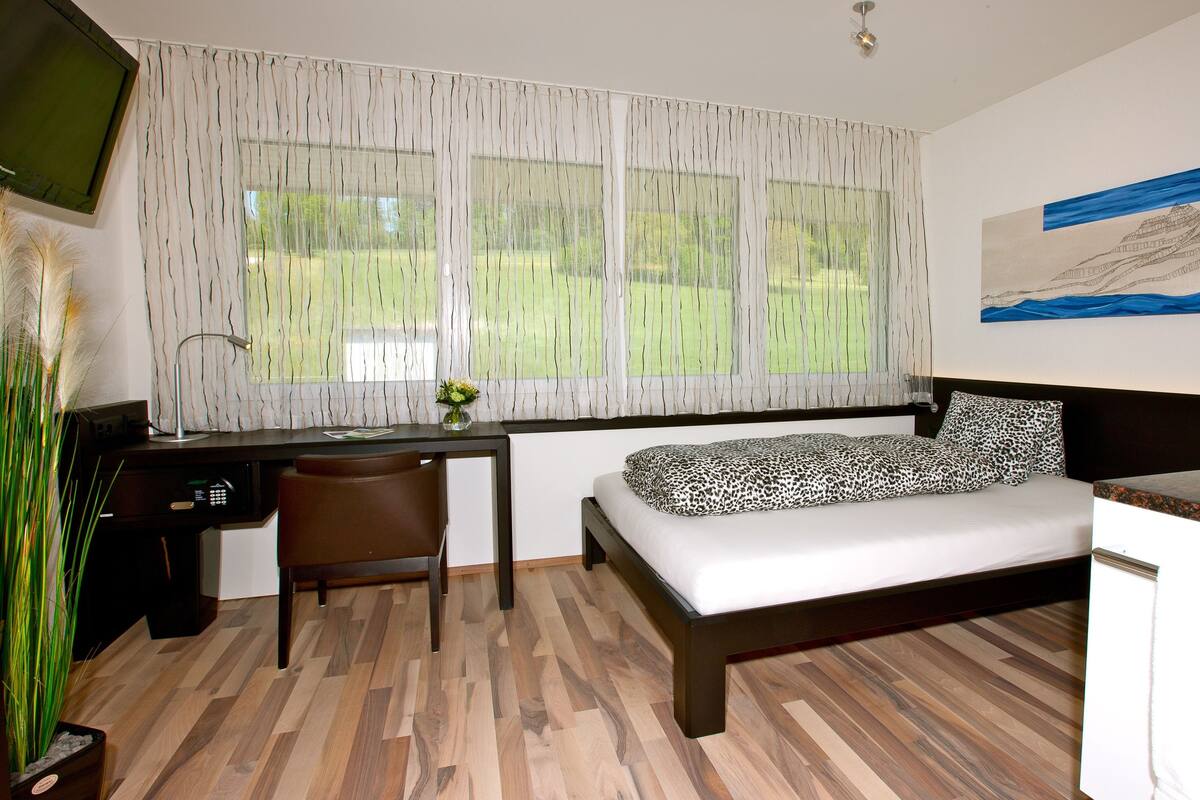 Un dormitorio con cama, escritorio, silla y un cuadro en la pared.
