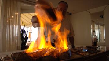 Una persona cocinando sobre una parrilla con fuego.