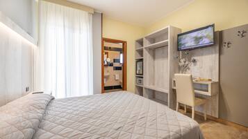 Quarto com cama, escrivaninha e televisão.