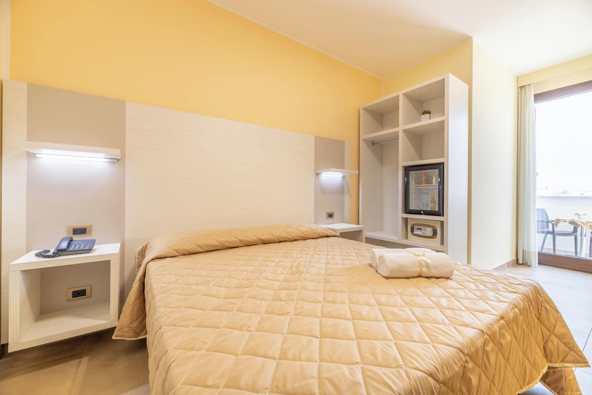 Habitación de hotel con cama, mesitas de noche, televisor y ventana con vistas.