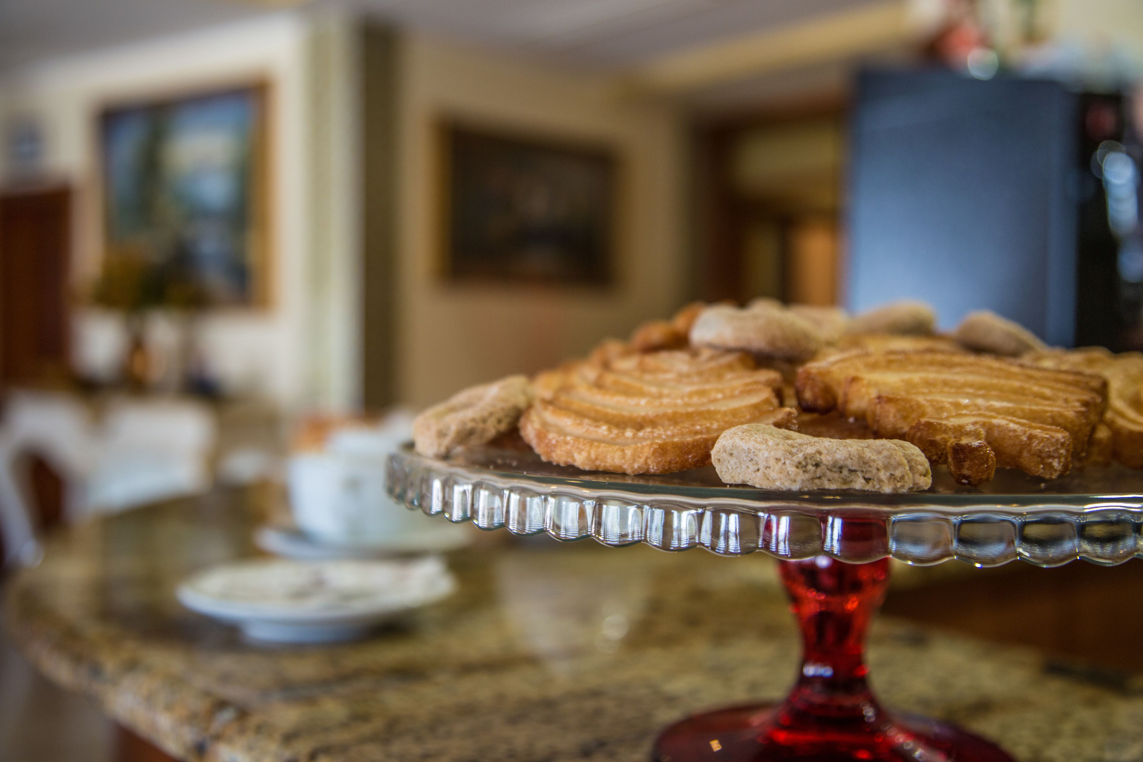 A glass cake stand with pastries on a kitchen counter.