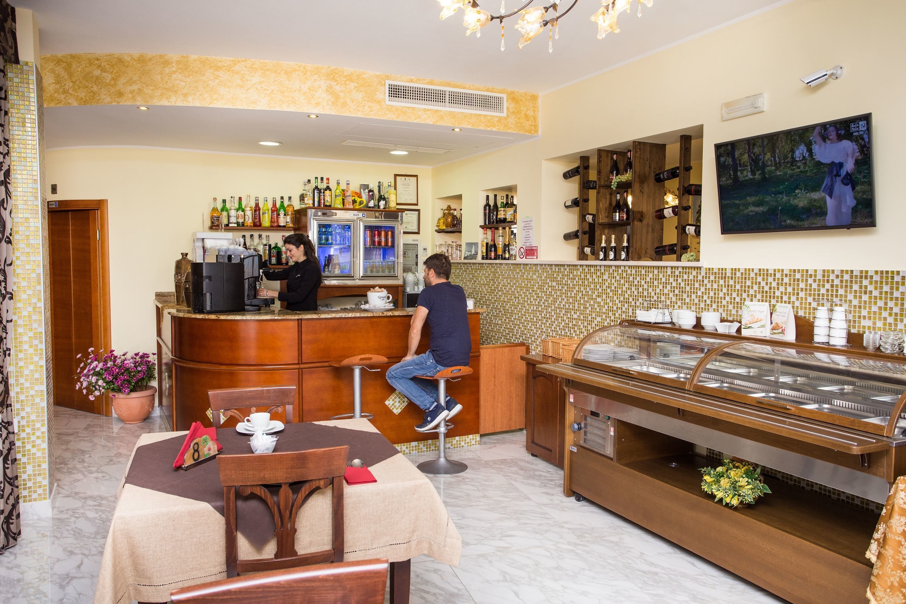 Zona de bar de hotel con mostrador, asientos y mesa de buffet.