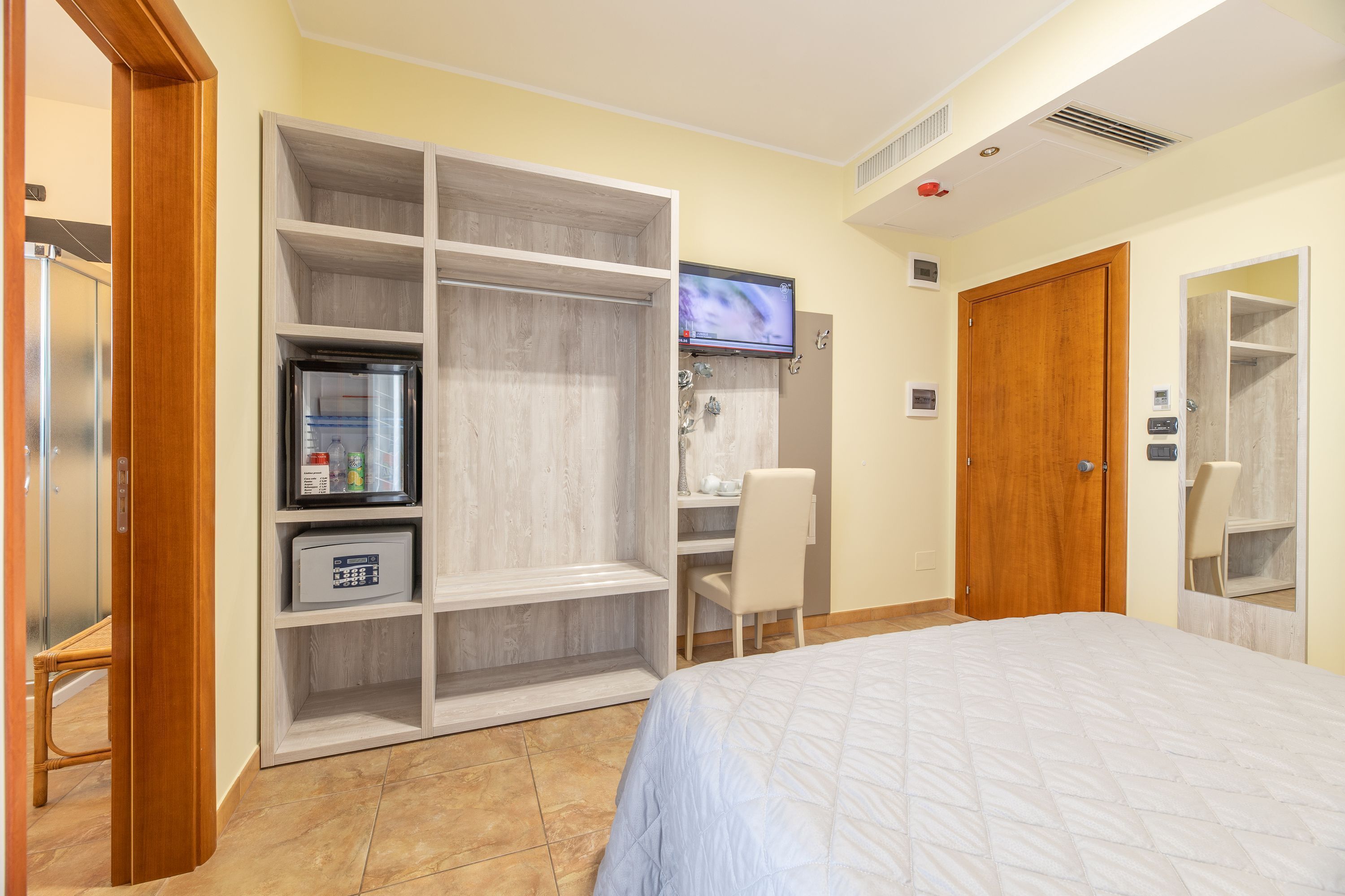 Un dormitorio con cama, armario, escritorio y televisor.