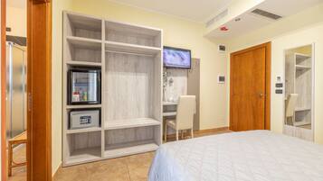 Un dormitorio con cama, armario, escritorio y televisor.
