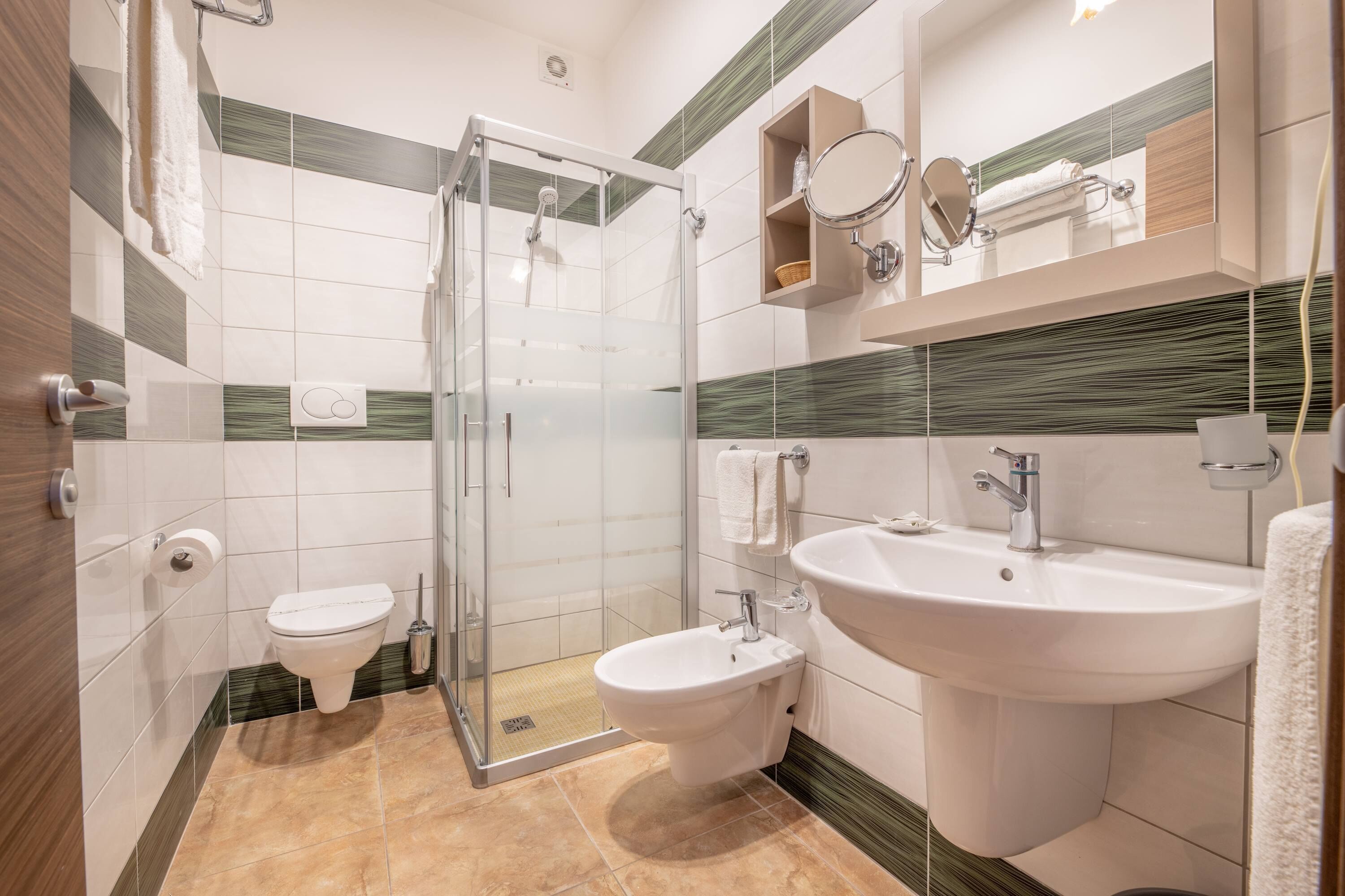 A modern bathroom with a glass-enclosed shower, a toilet, a bidet, and a sink.