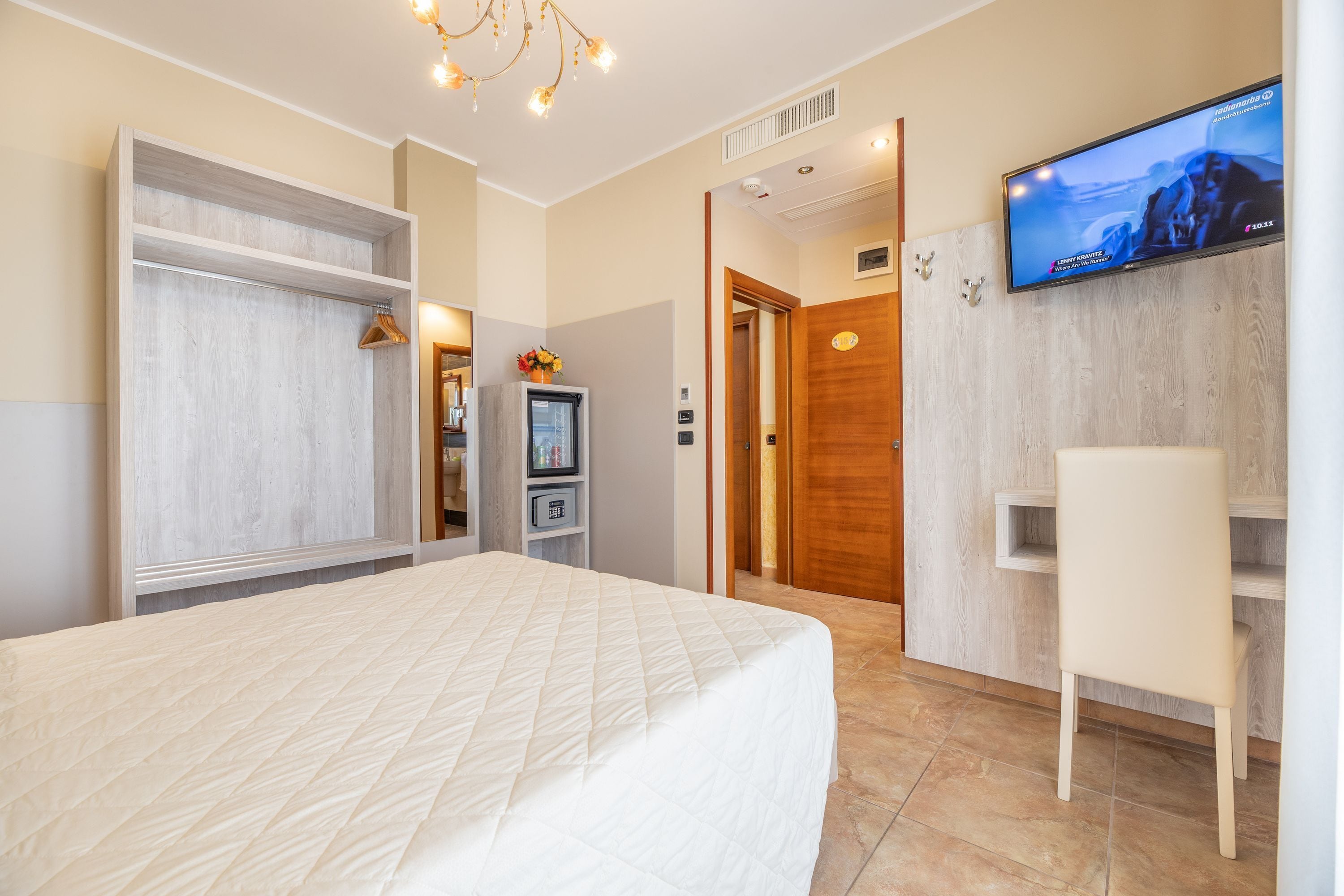 Ein Hotelzimmer mit Bett, Fernseher, Schreibtisch und Kleiderschrank.