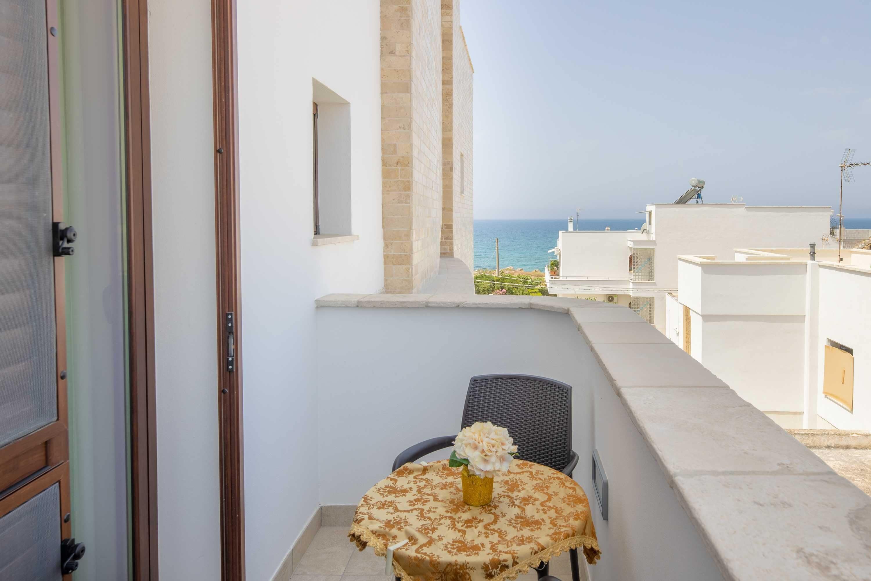 Ein Balkon mit Tisch und Stuhl mit Blick auf die Küste.