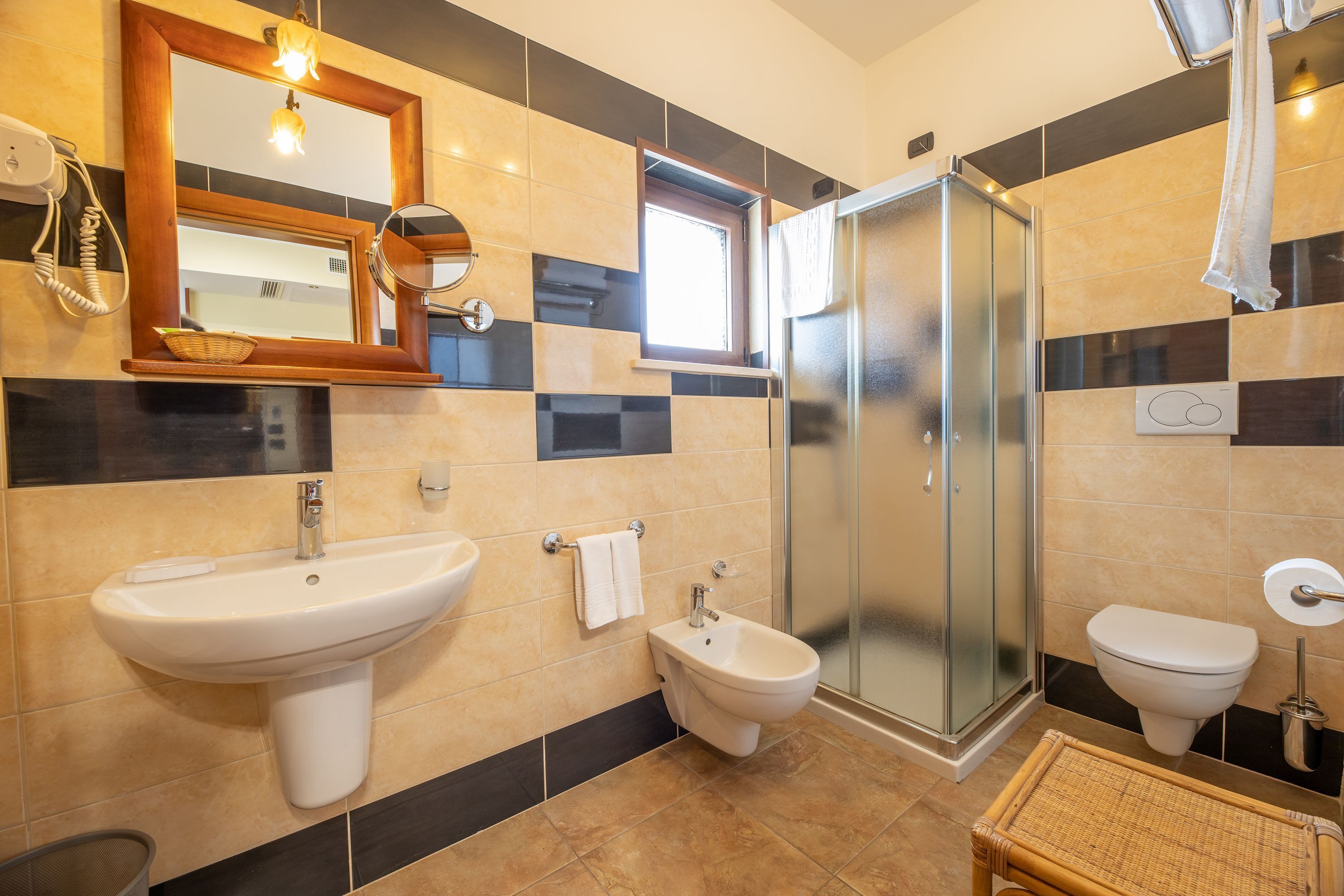 Et badeværelse med håndvask, bidet, toilet og en brusekabine med glasvægge.