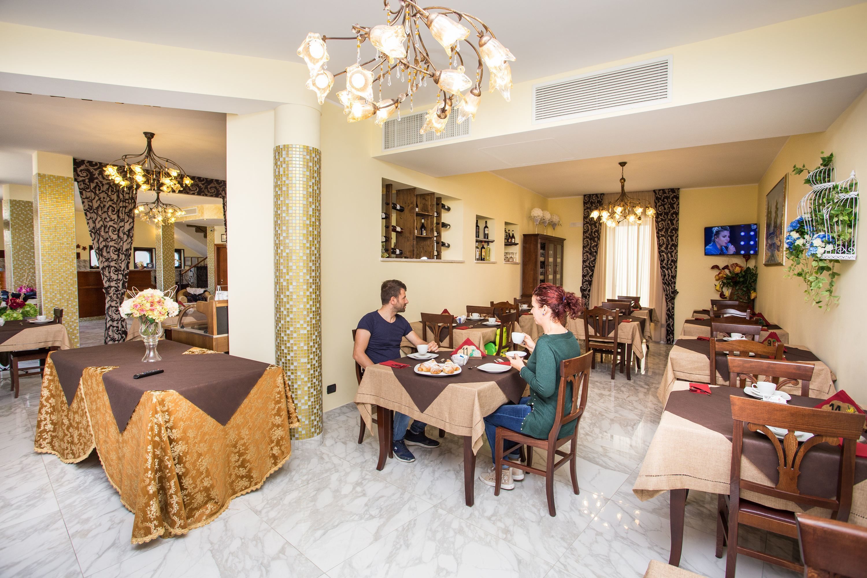A dining area with multiple tables, chairs, and a chandelier.