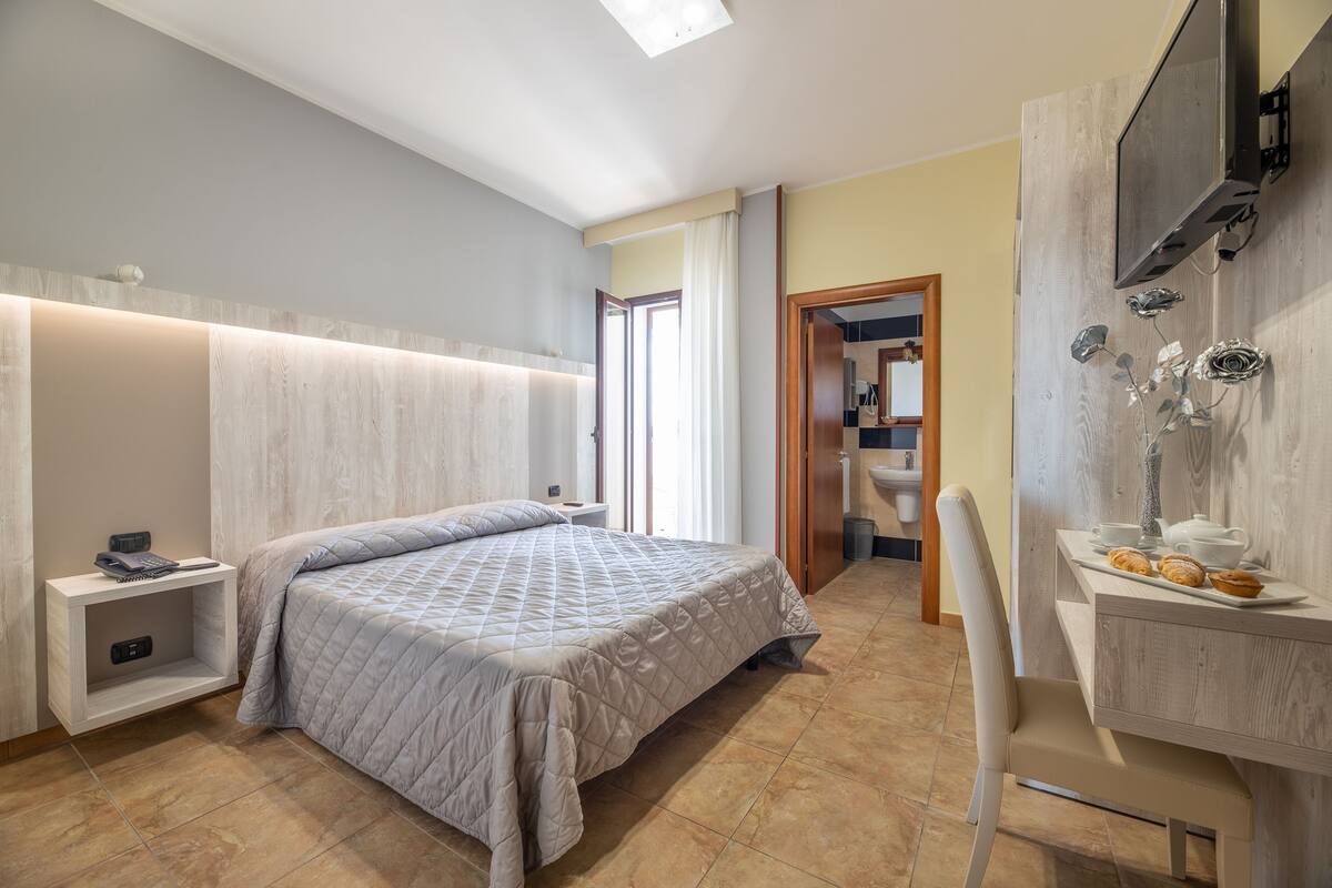 Un dormitorio moderno con cama, mesita de noche y escritorio con silla.