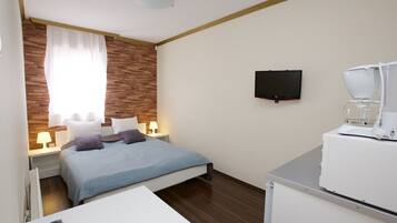 Een hotelkamer met een bed, een bureau, een koffiezetapparaat, een televisie en een raam met gordijnen.
