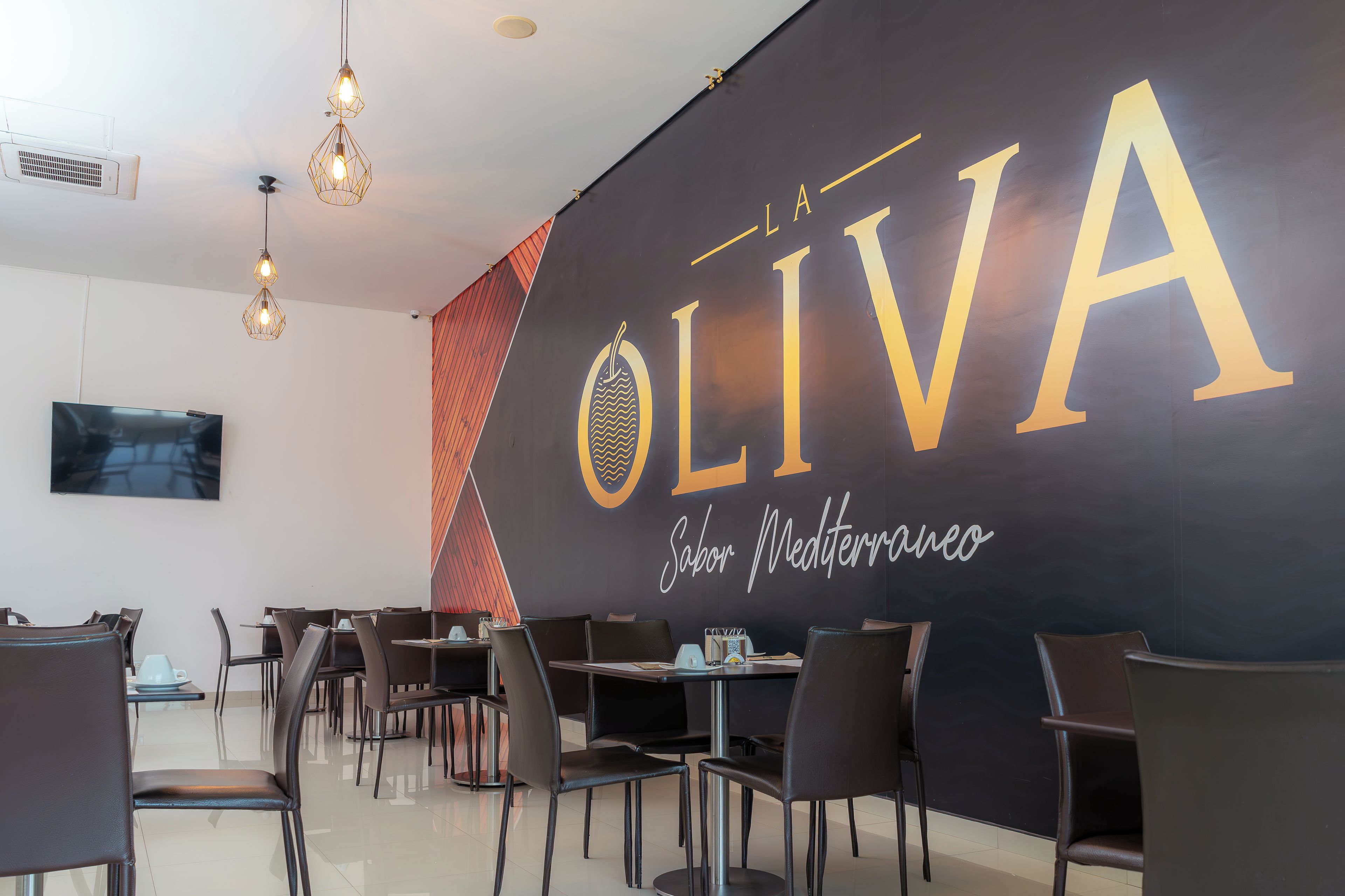 Een moderne eethoek met een groot bord waarop 'OLIVA' en 'Sabor Mediterraneo' staan.