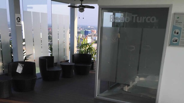 A rooftop terrace with a hot tub, outdoor seating, and a view of the city.